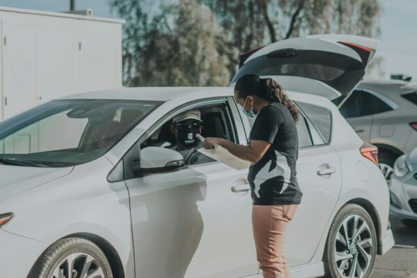 woman in black and white shirt and orange shorts leaning on white car during daytime