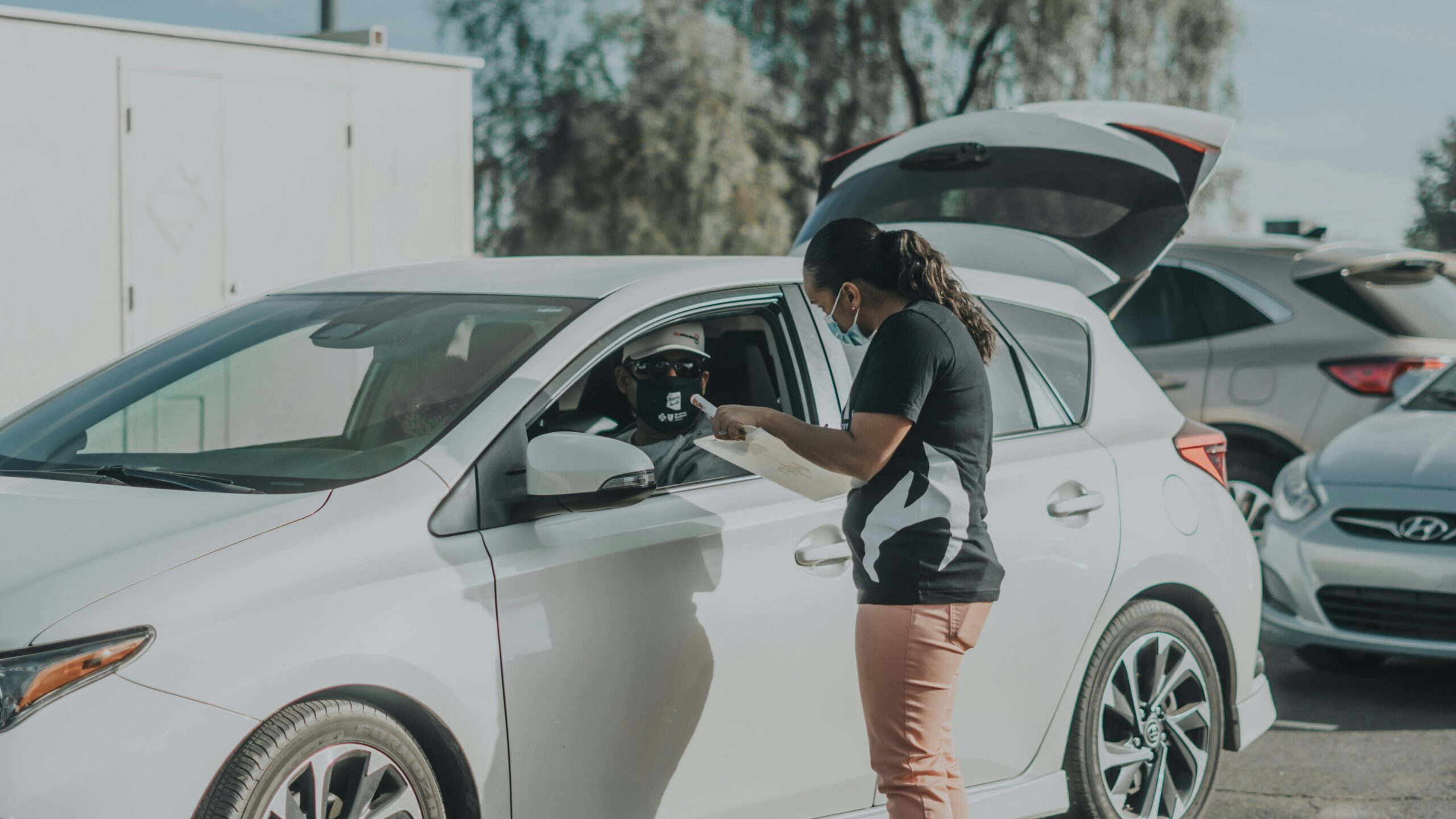 woman in black and white shirt and orange shorts leaning on white car during daytime