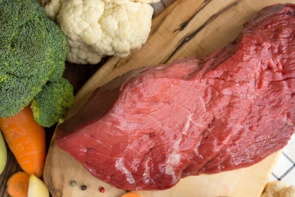 Beef tenderloin and vegetables on rustic wooden background