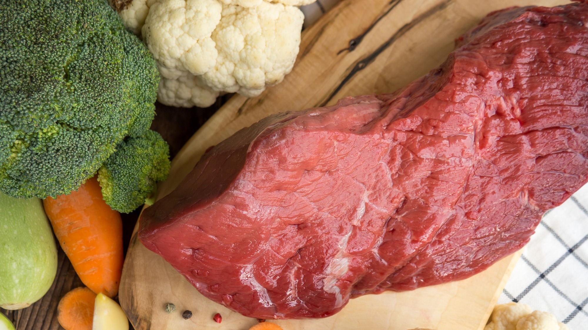 Beef tenderloin and vegetables on rustic wooden background