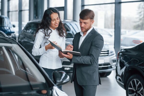Where I need to sign. Female customer and modern stylish bearded businessman in the automobile saloon
