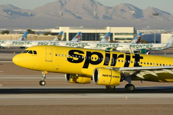 A yellow spirit airplane on the runway of an airport