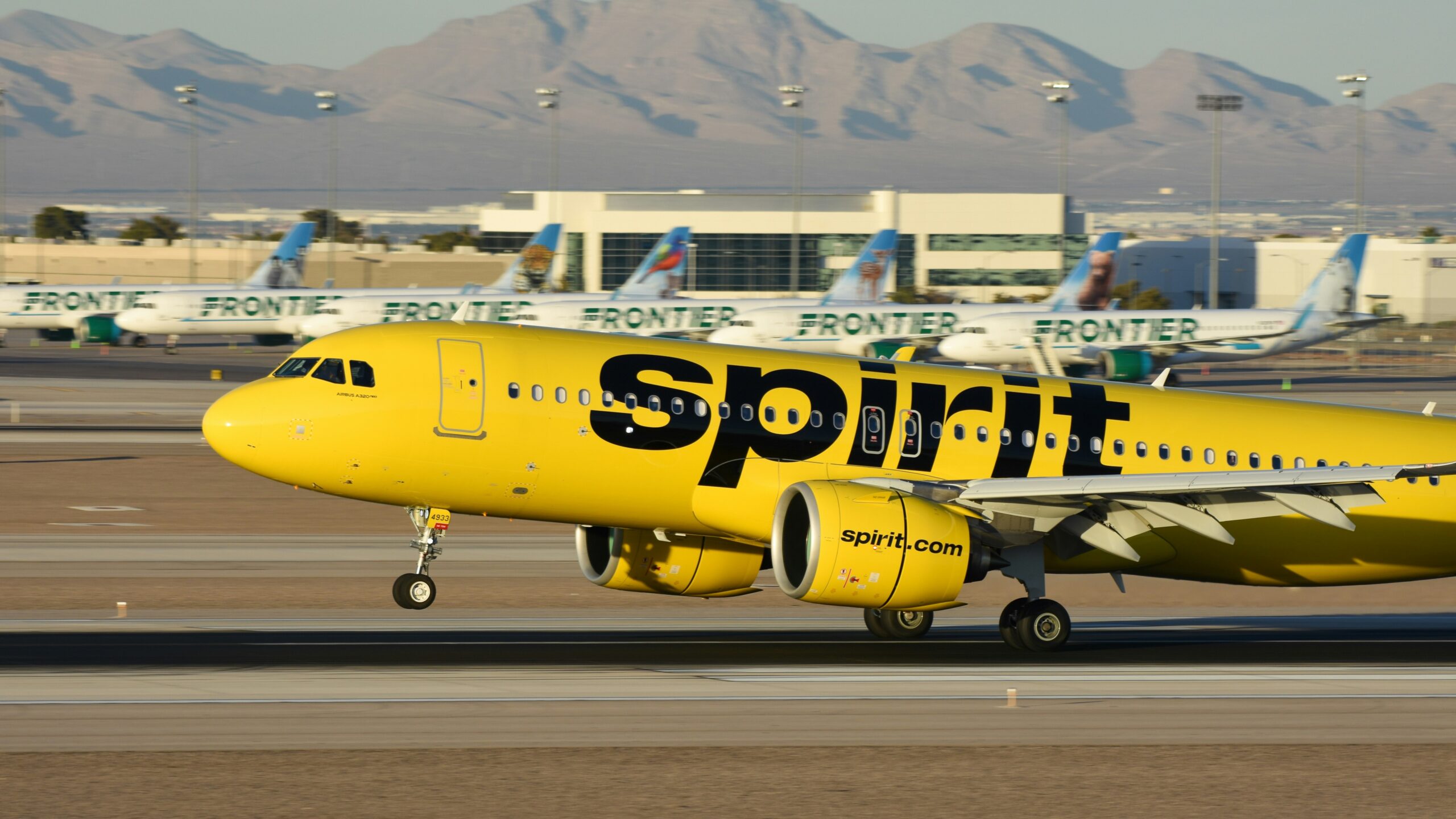 A yellow spirit airplane on the runway of an airport