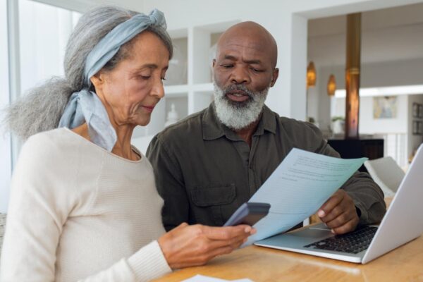Couple discussing papers and using laptop inside a room
