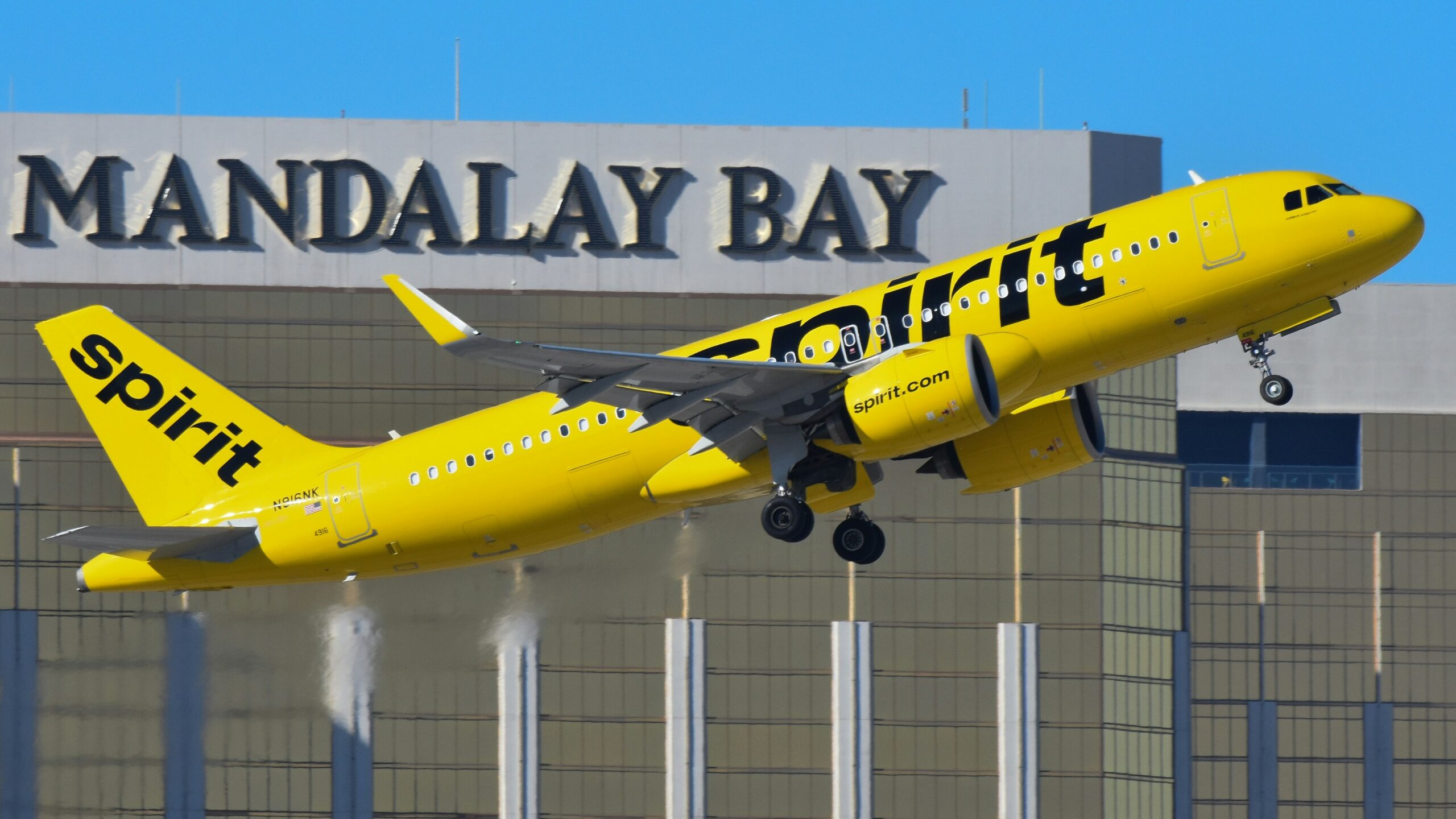 A yellow and black jet airliner taking off from an airport