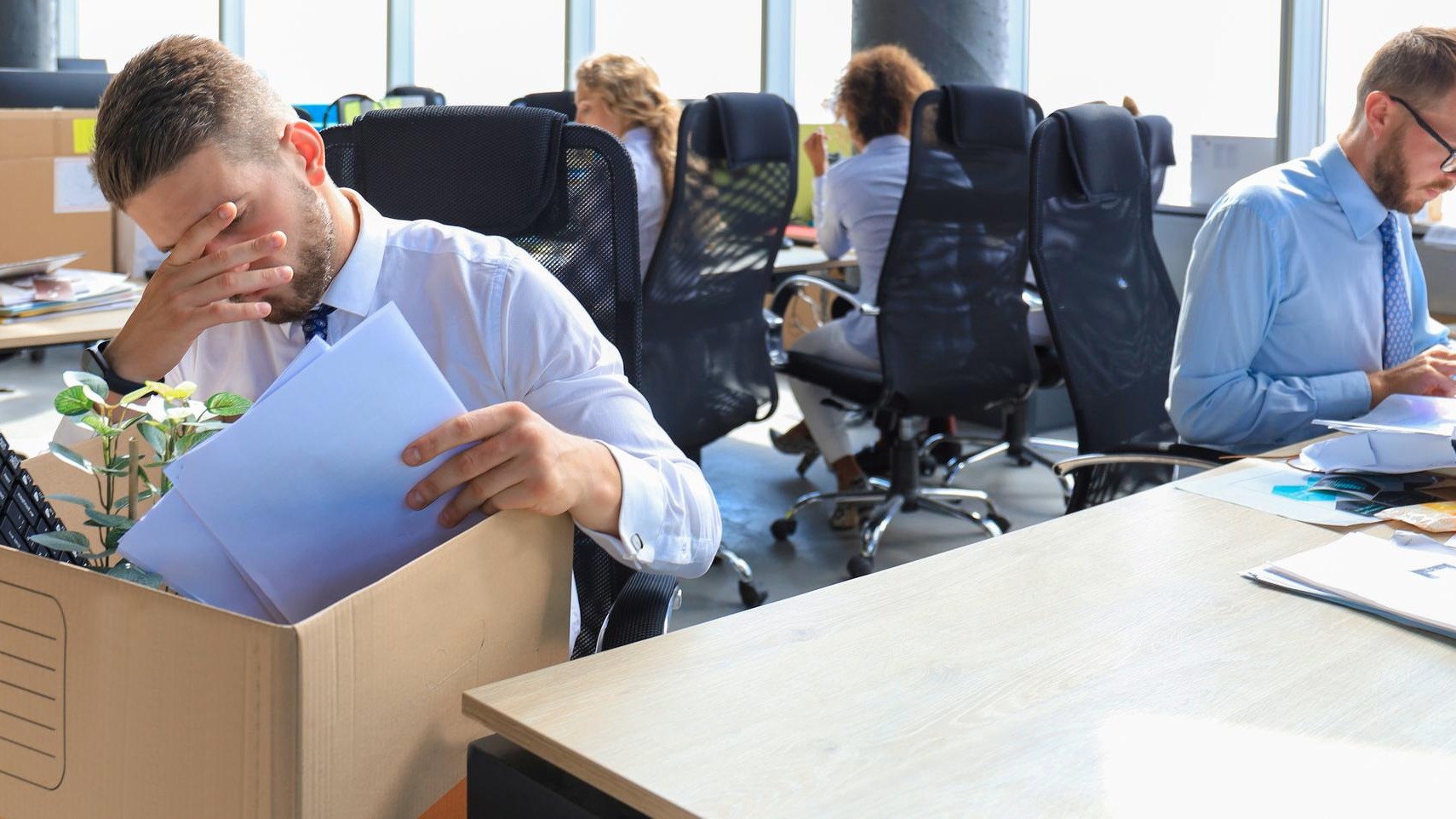 Sad dismissed worker are taking his office supplies with him from office