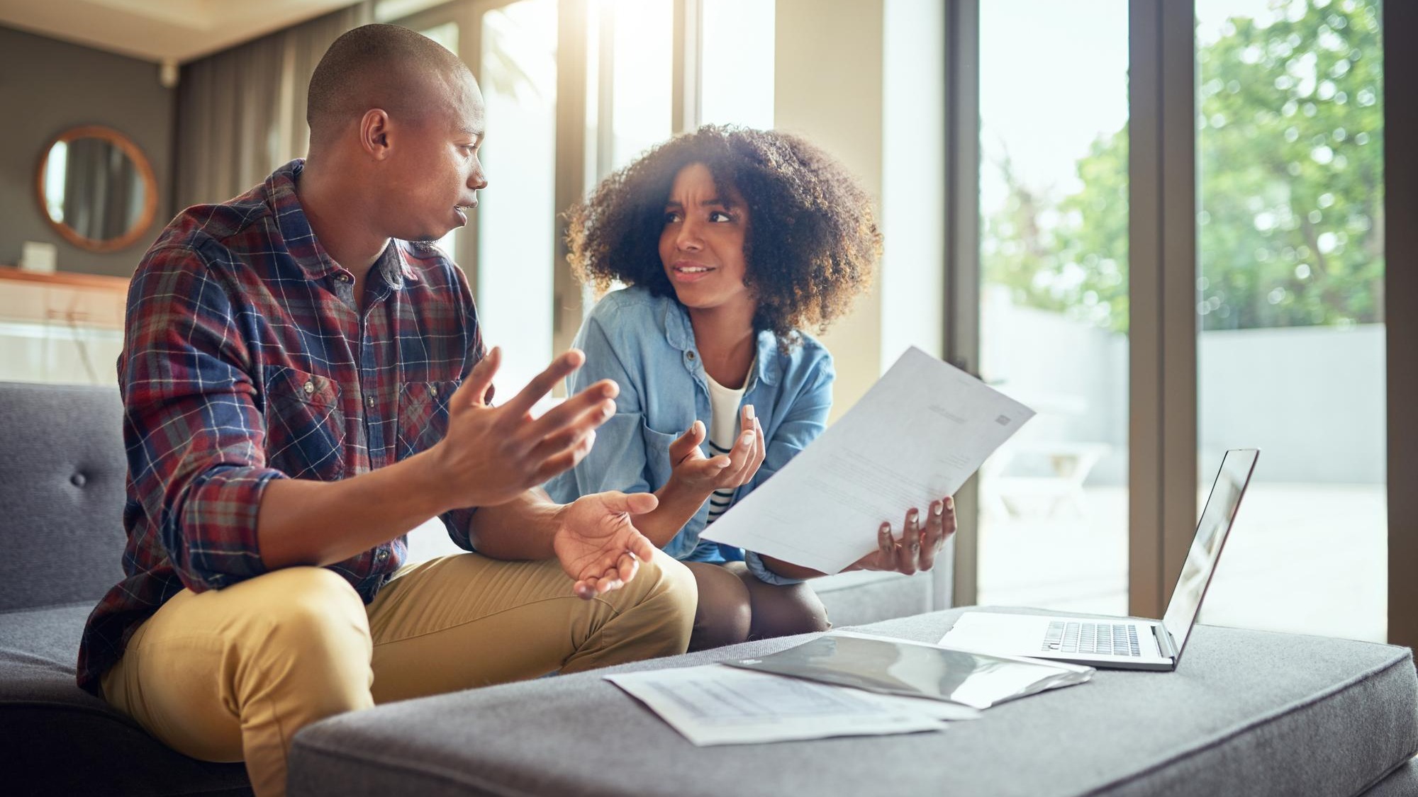 Financial paperwork planning or couple with questions finance documents or budget in home Receipt laptop or worried people speaking of bills doubt or debt with recession taxes or inflation