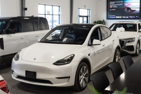 White tesla model y parked inside a showroom.