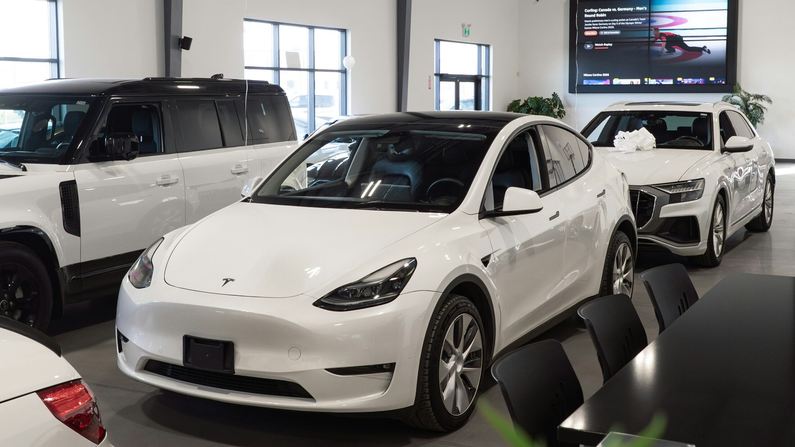 White tesla model y parked inside a showroom.