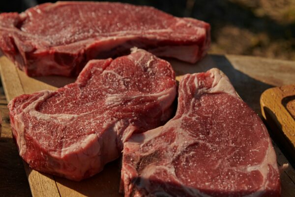 a couple of steaks sitting on top of a wooden cutting board