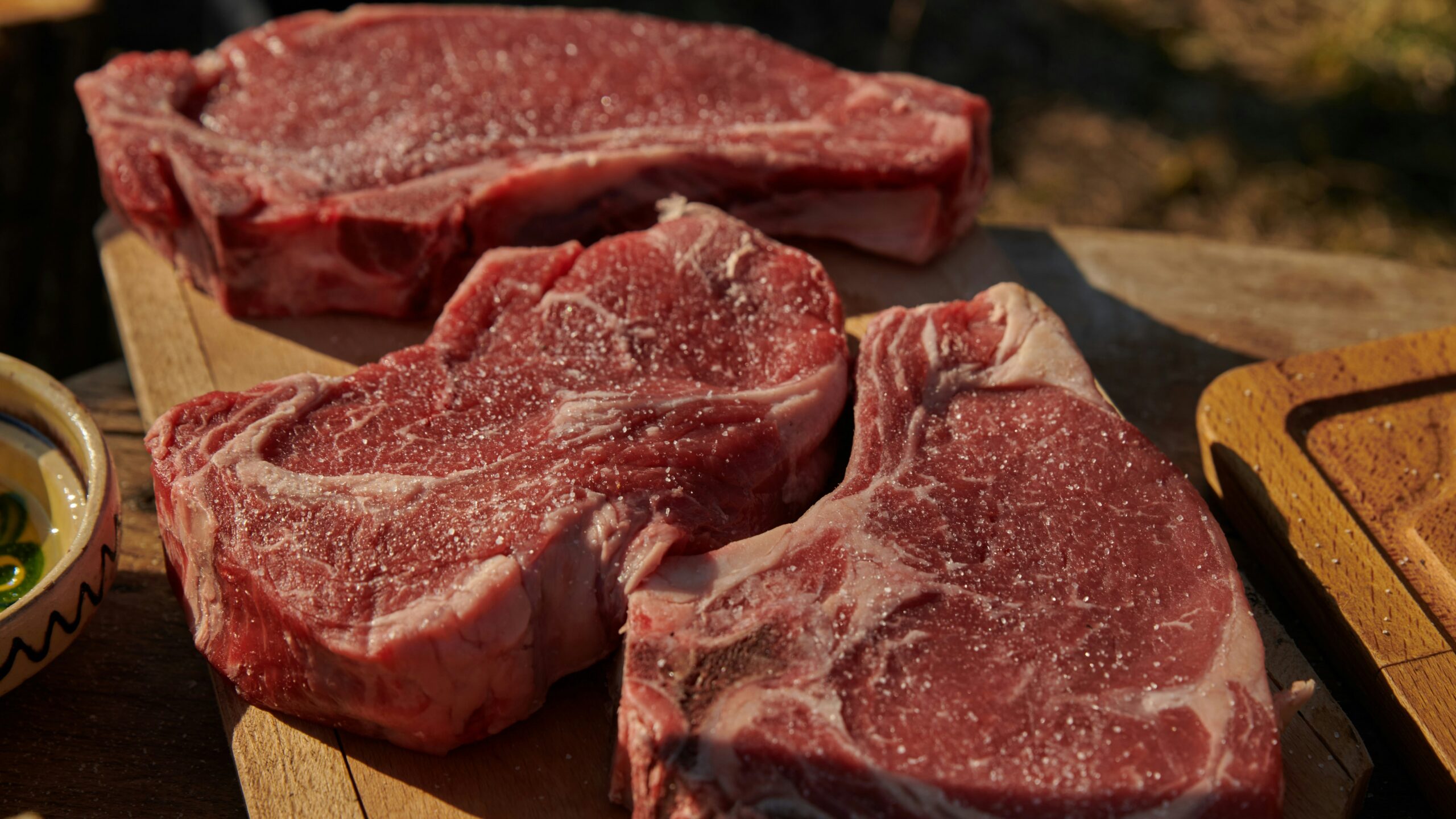 a couple of steaks sitting on top of a wooden cutting board