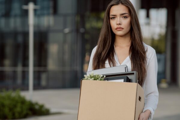 Woman stands in front of glass modern building of corporation office where she worked