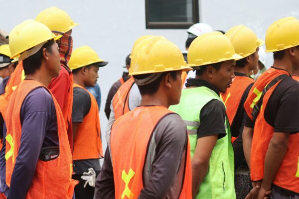 man in orange vest wearing yellow hard hat