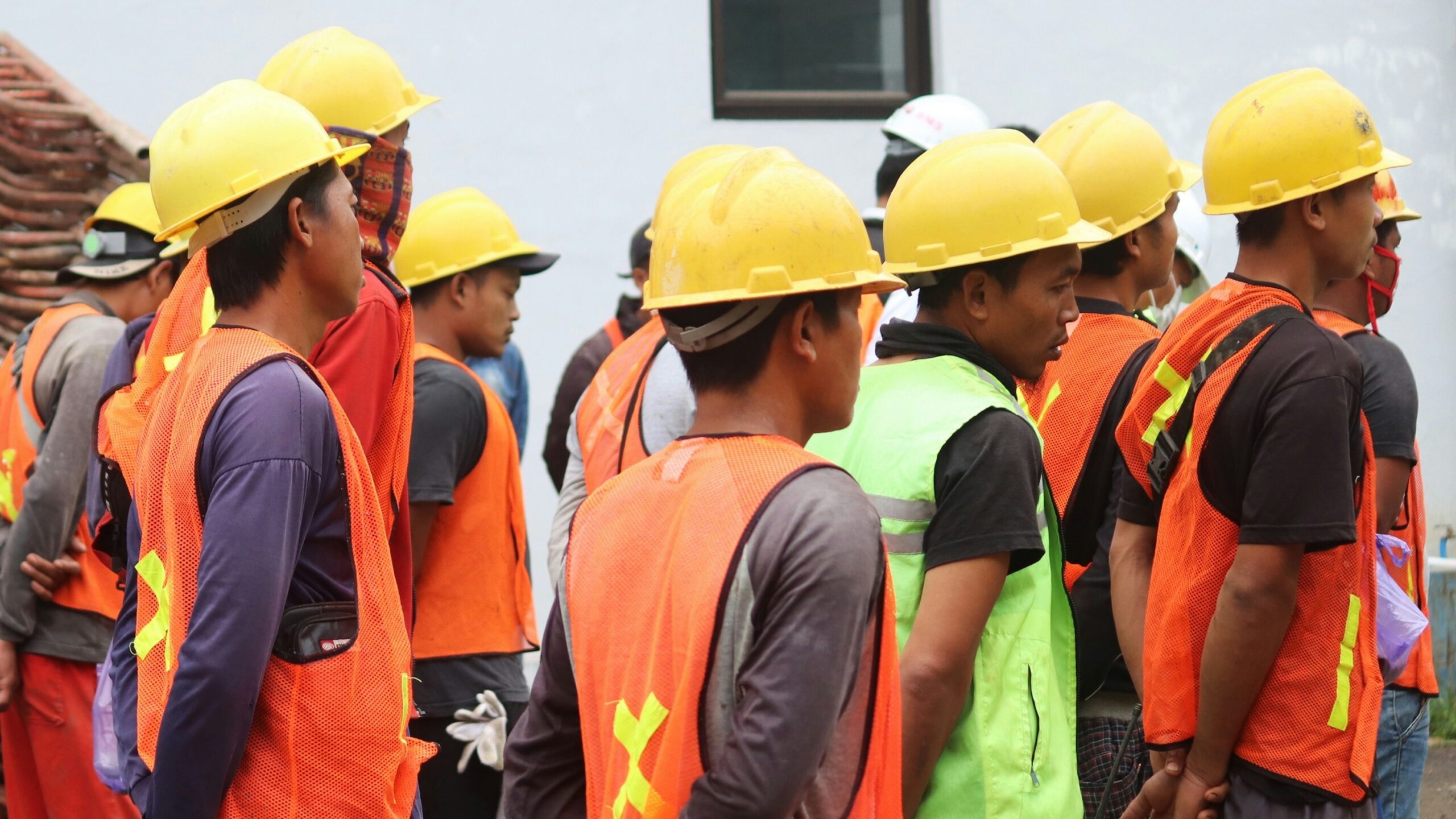 man in orange vest wearing yellow hard hat