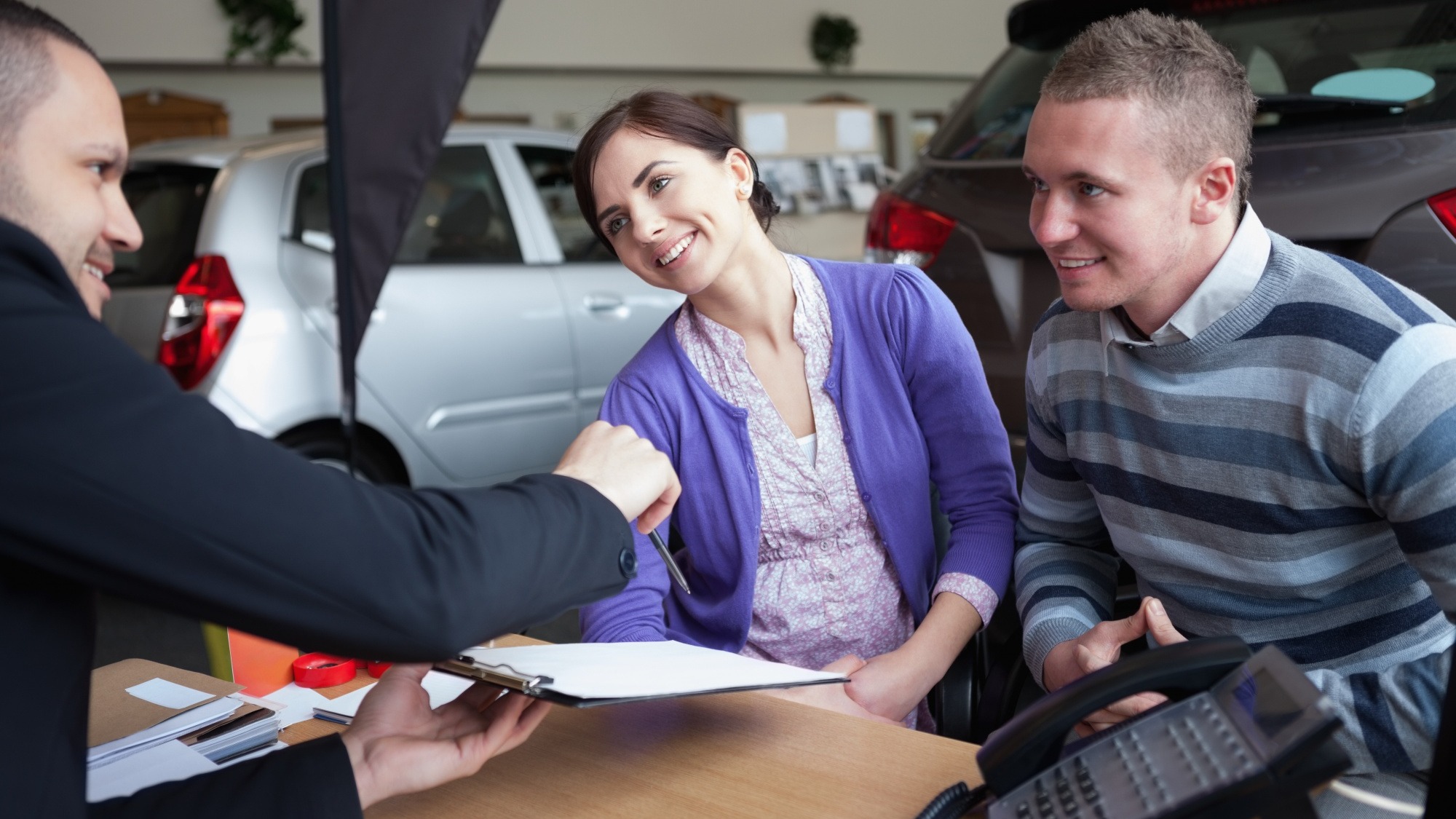 Couple chatting with a car salesman