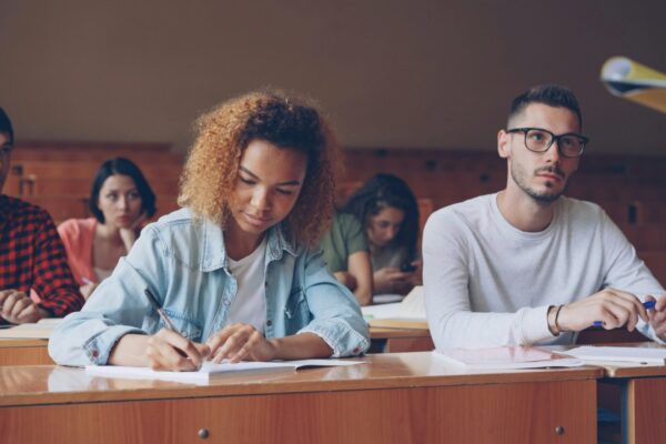 Students attentively taking notes in a lecture hall.