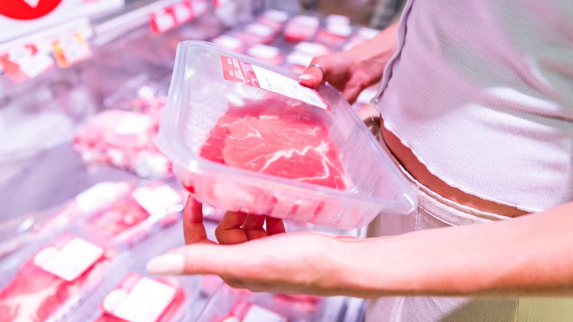 Closeup of the hands of a woman who is choosing the meat to buy at the supermarket