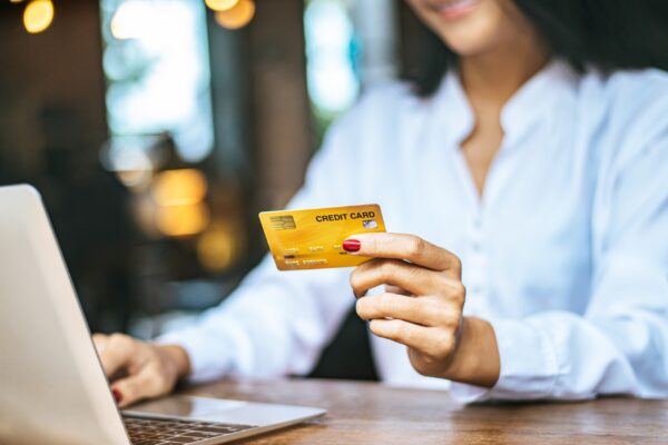 woman sat with a laptop and paid with a credit card in a cafe