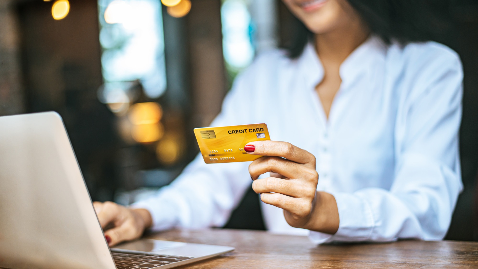 woman sat with a laptop and paid with a credit card in a cafe