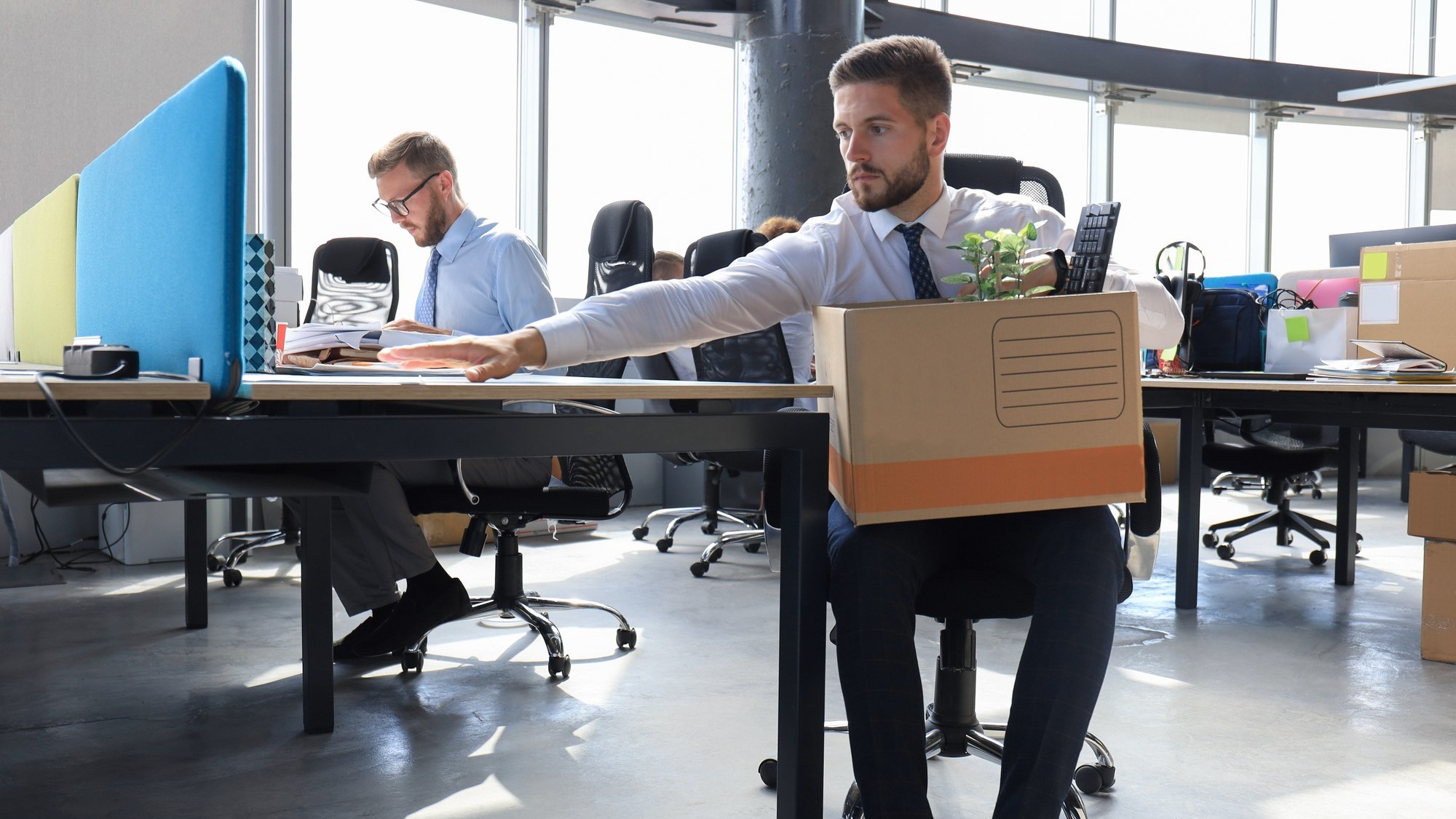 Sad dismissed worker are taking his office supplies with him from office.