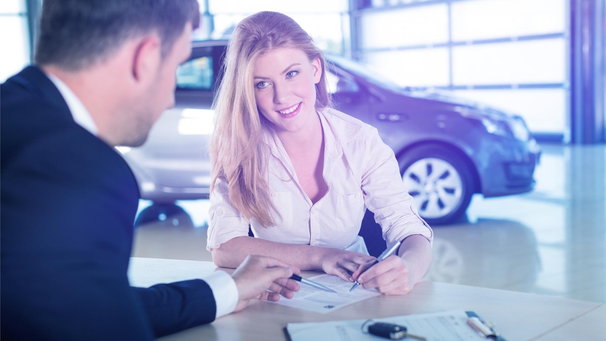 Happy woman with car dealer in auto show or salon