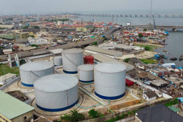 Large industrial tanks sit near a cityscape.