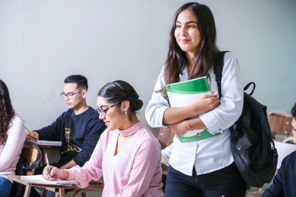 woman carrying white and green textbook