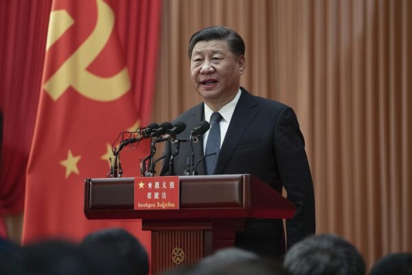 Confident Chinese President Xi Jinping giving a speech at a podium with red flags in the background
