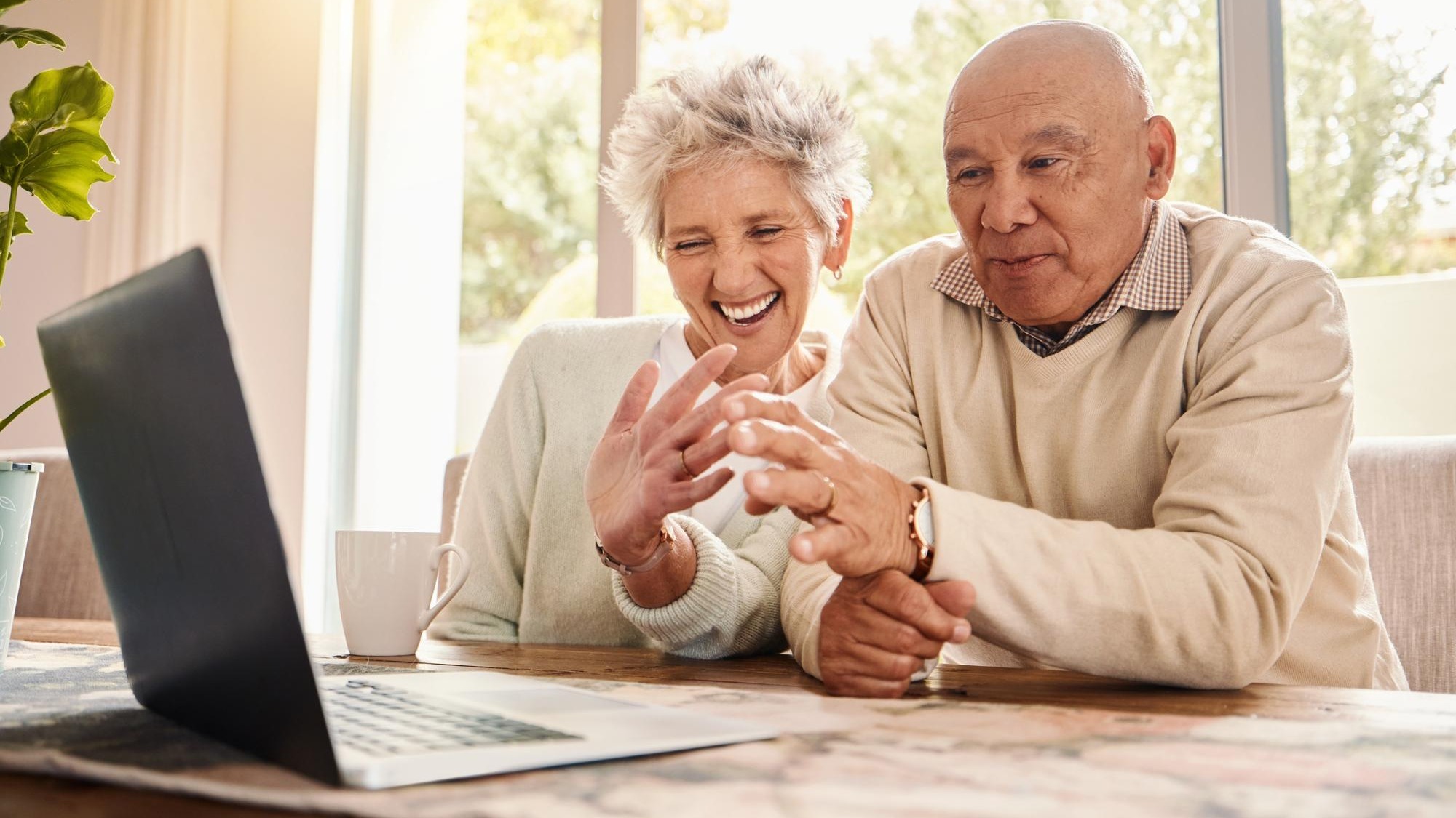Laptop video call and senior couple wave talking to contact and laughing in home Comic technology and smile of happy retired man and woman with computer for virtual chat or online communication