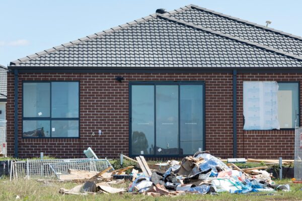 Construction debris piled in front of a brick house