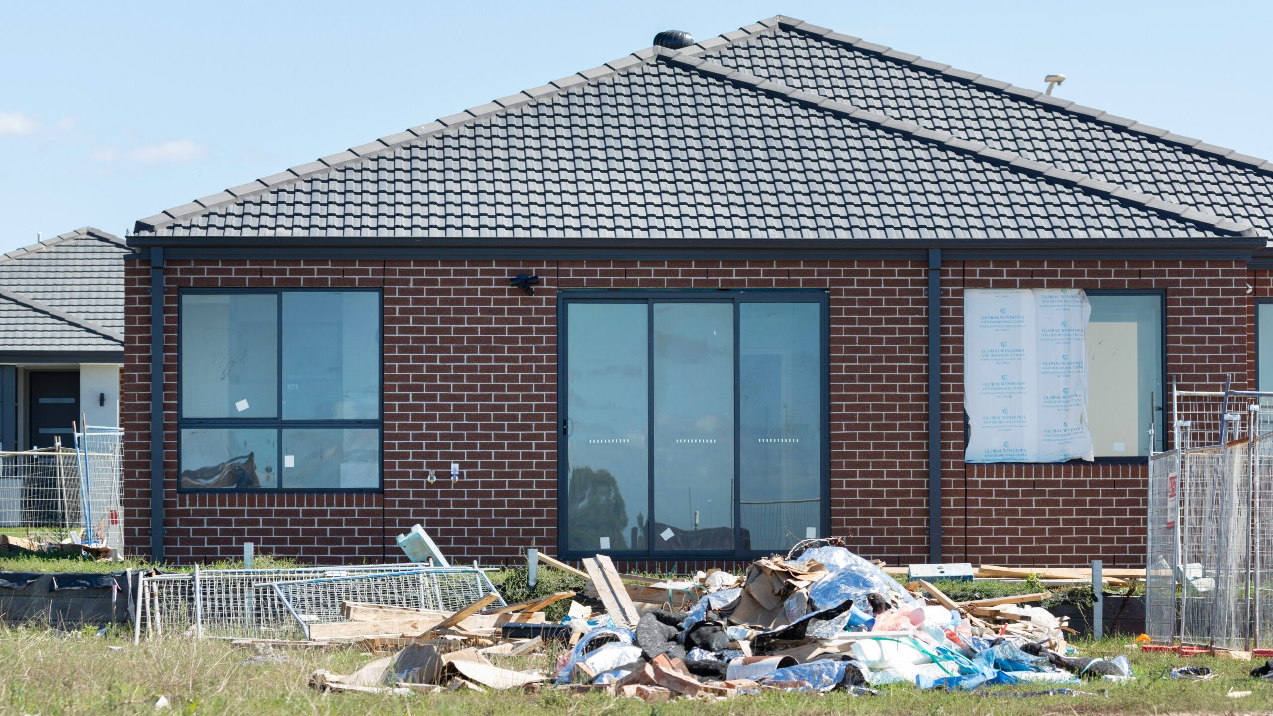 Construction debris piled in front of a brick house
