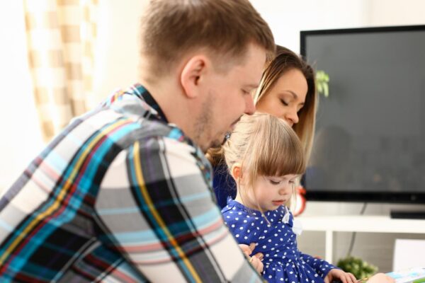 Happy parents with daughter at sofa at home