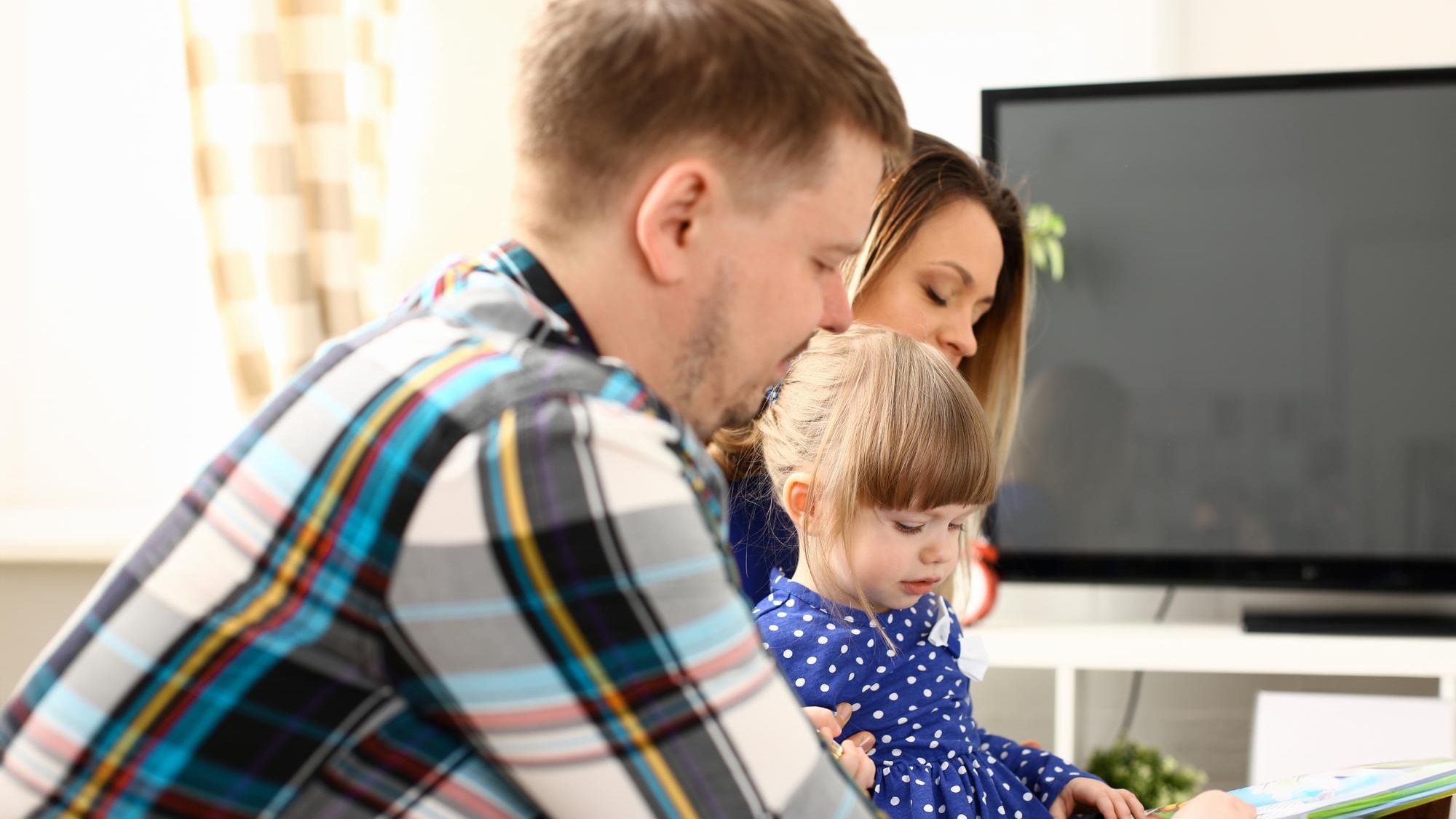 Happy parents with daughter at sofa at home