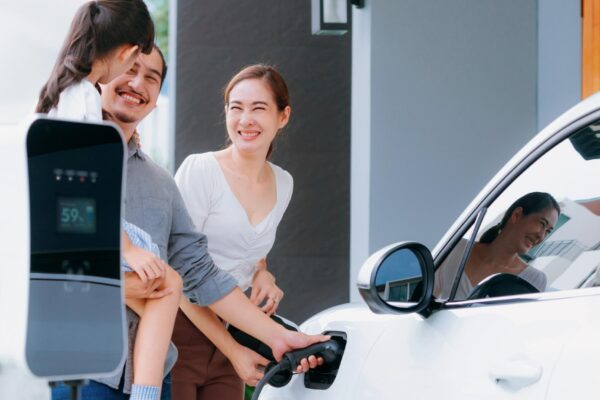 Progressive young parents and daughter living in a home with an electric car