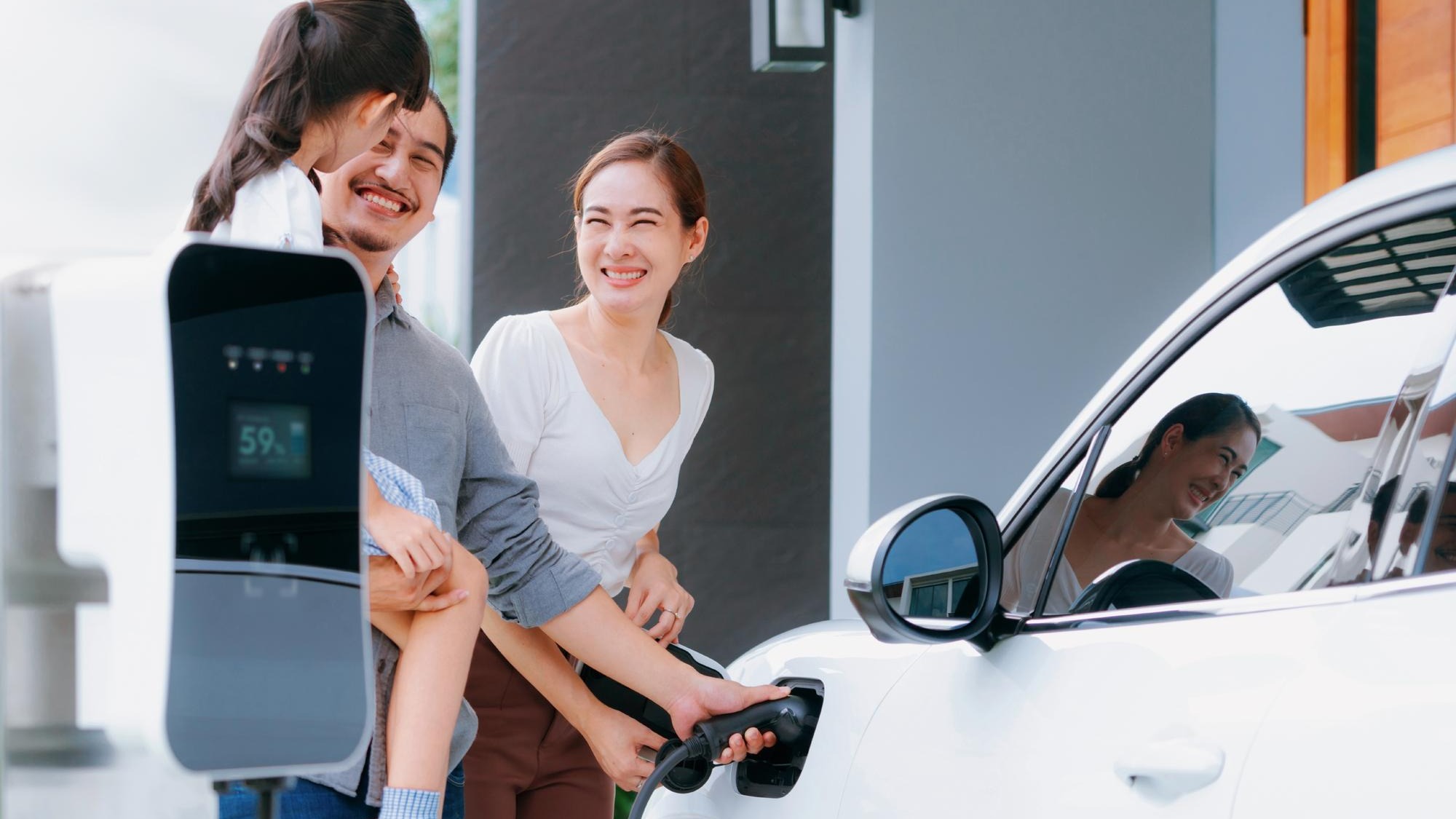 Progressive young parents and daughter living in a home with an electric car