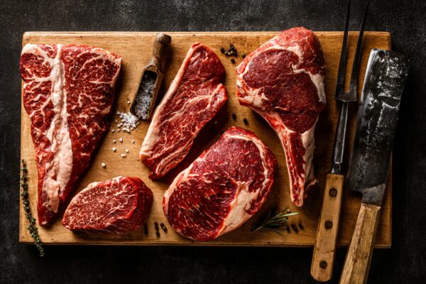 a cutting board with steaks and a knife on it