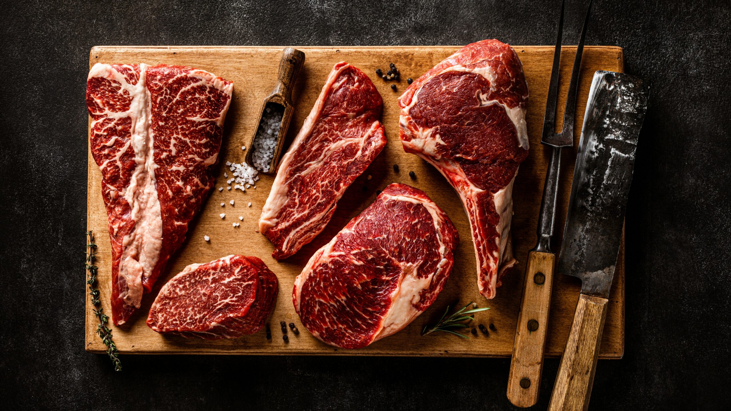 a cutting board with steaks and a knife on it