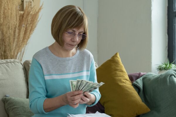 Senior mature woman using calculator holding paper bill calculating money budget tax