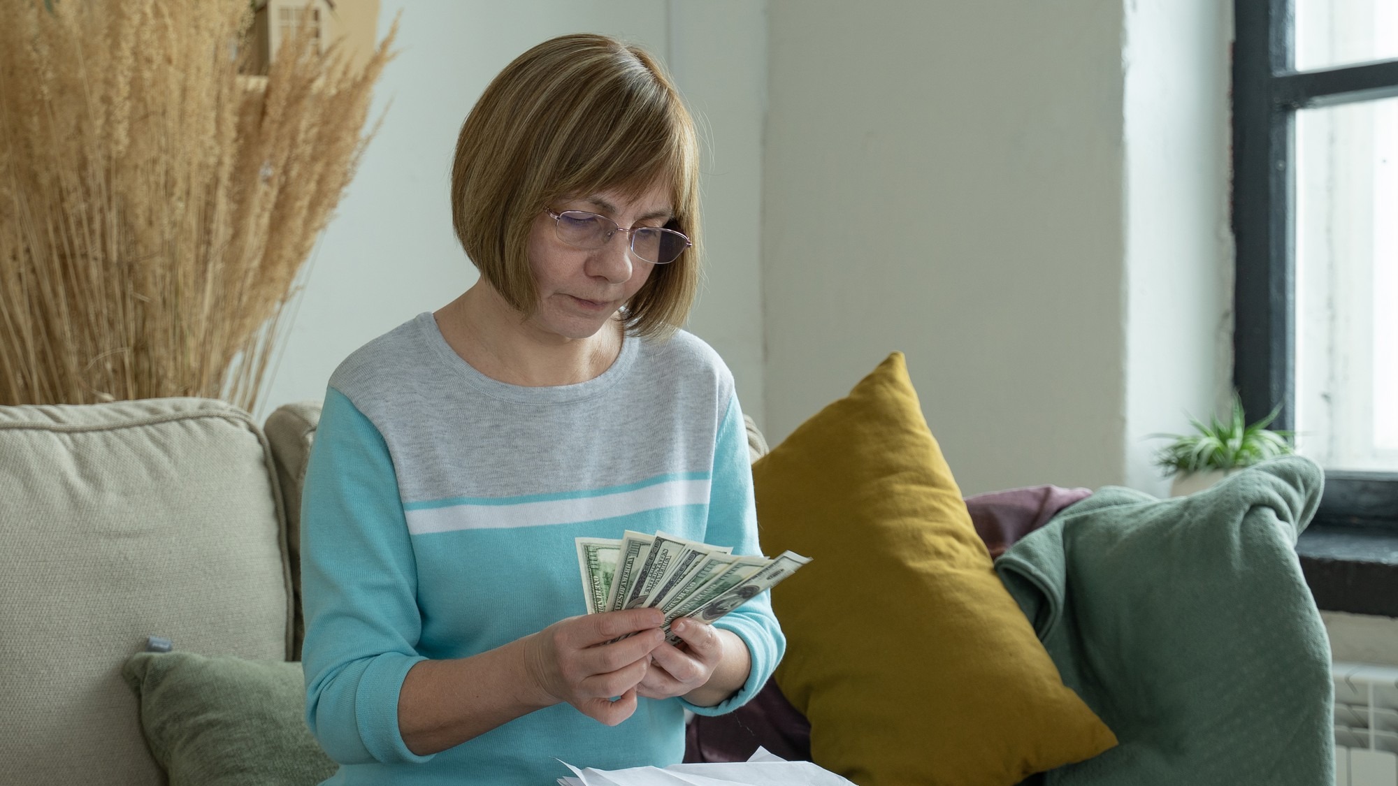Senior mature woman using calculator holding paper bill calculating money budget tax