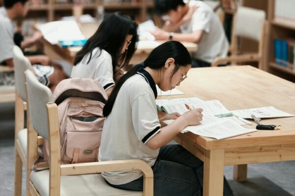 Students studying at tables in a library.