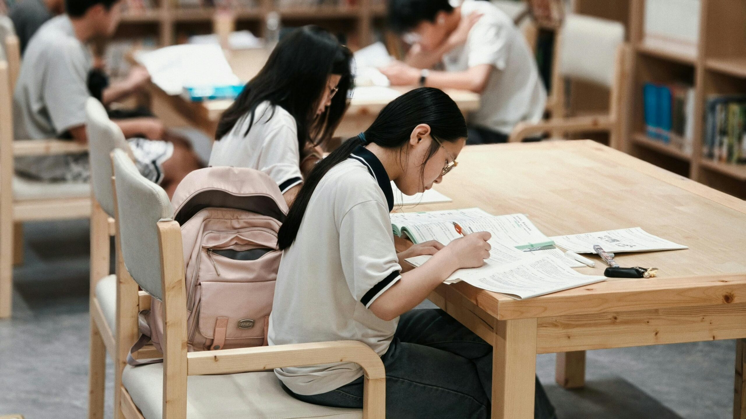 Students studying at tables in a library.