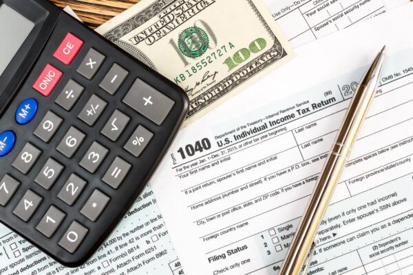 Calculator with one hundred dollar bill on the tax form Top view