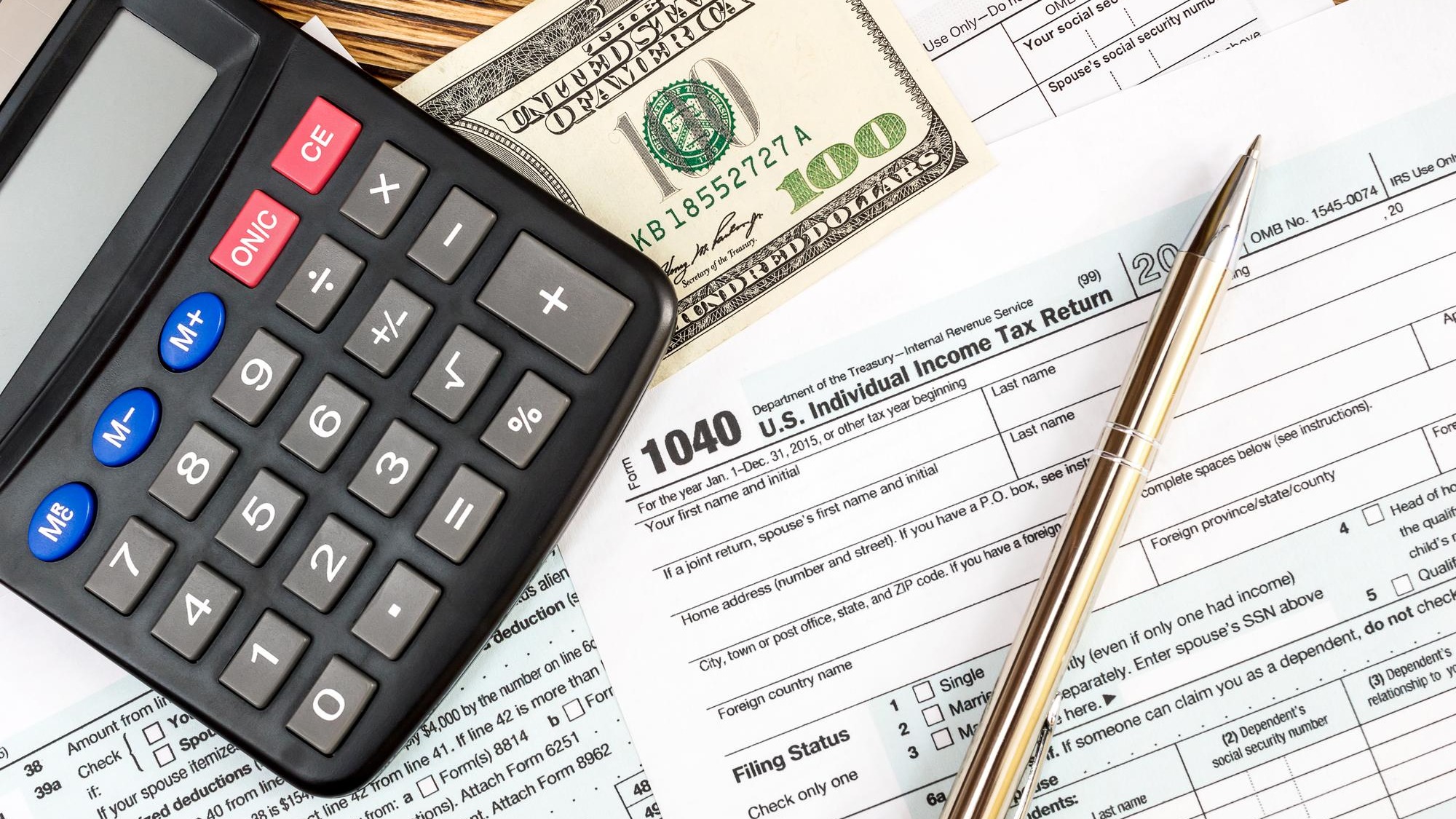 Calculator with one hundred dollar bill on the tax form Top view