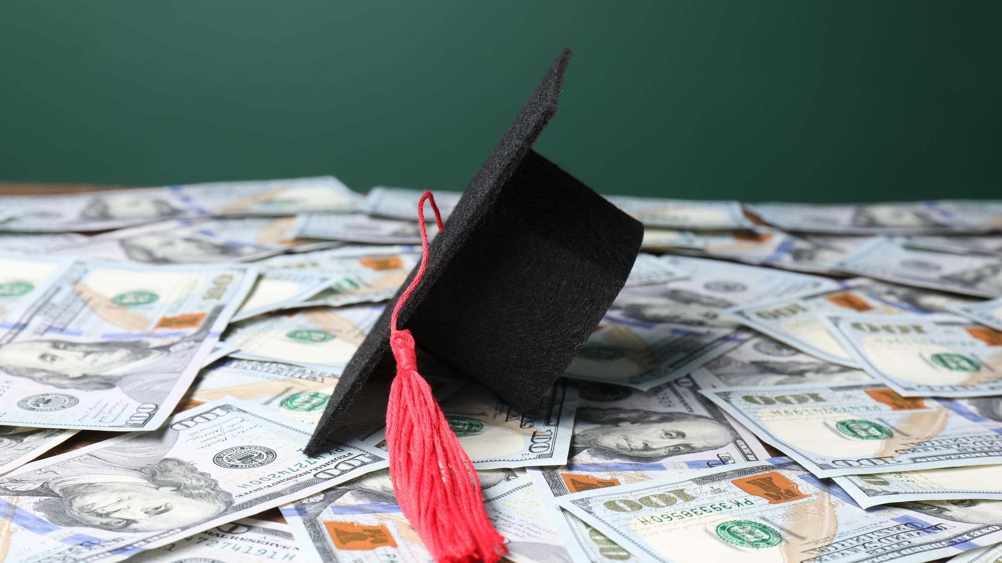 Graduate hat on dollar banknotes closeup Tuition payment