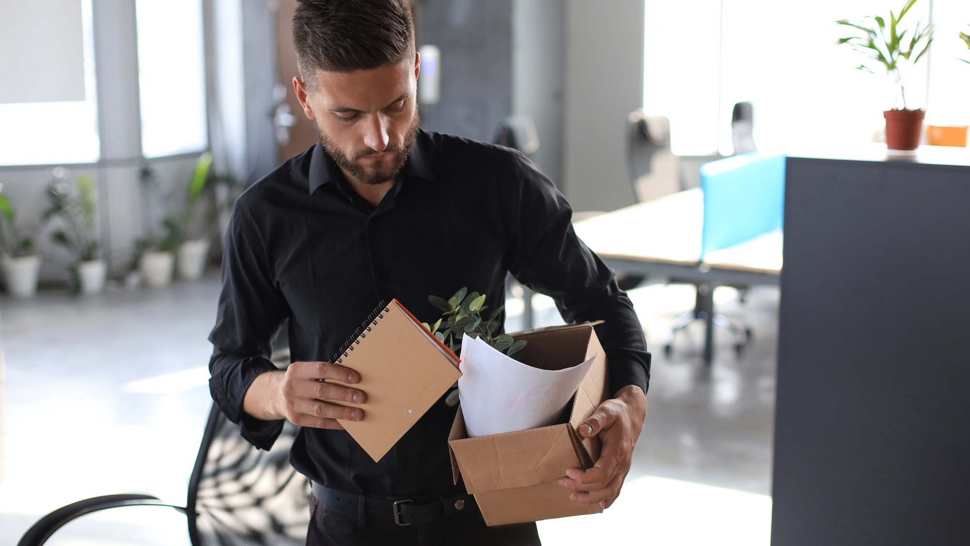 Sad dismissed worker is taking his office supplies with him from office.