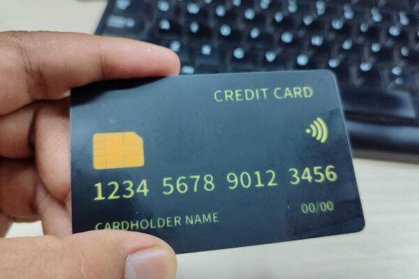 A hand holding a black credit card