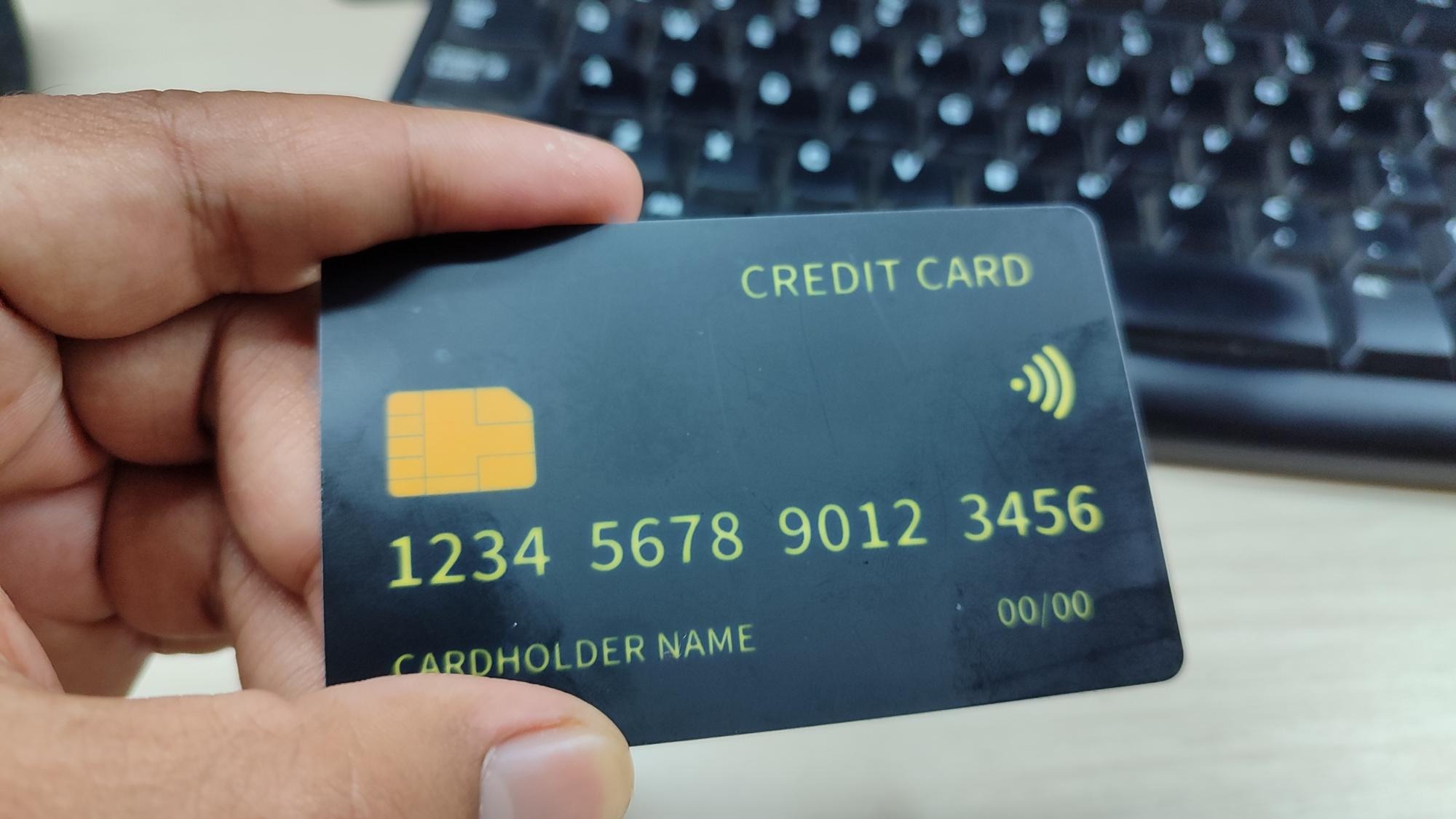 A hand holding a black credit card