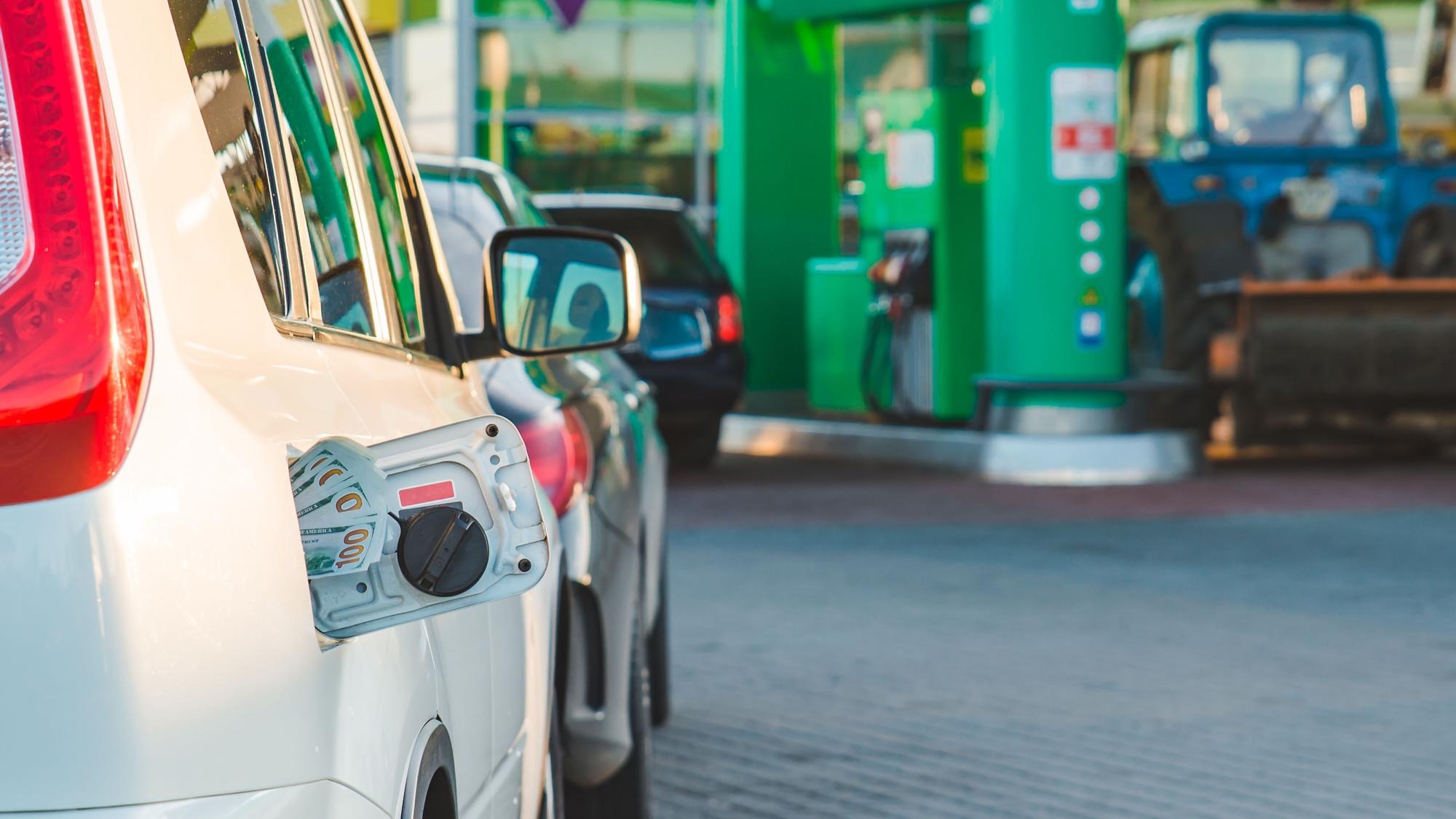 car with money in tank gas station on background copy space