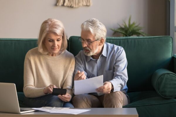 Serious mature couple calculating bills checking domestic finances
