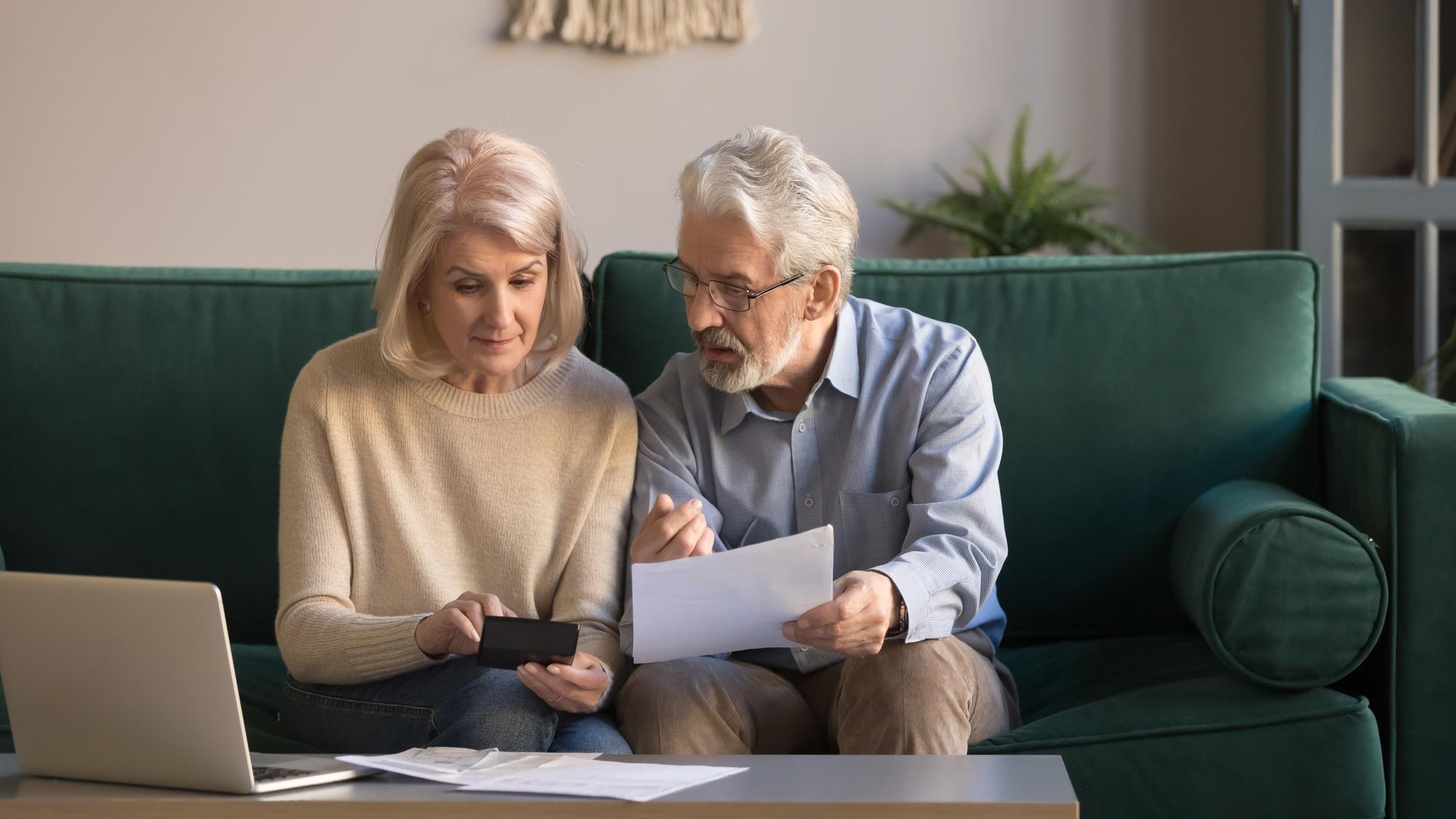 Serious mature couple calculating bills checking domestic finances